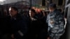 Migrant workers pass policemen as they board a train bound for Tajikistan in Moscow, October 7, 2011. 
